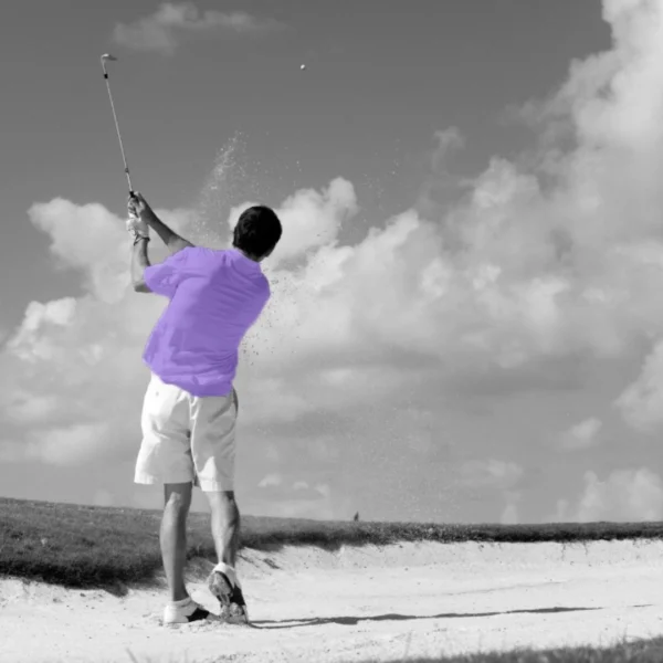 Golfer in a purple shirt in a sand trap making a shot